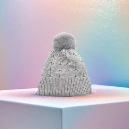 A grey knitted cap with a fluffy ball on top for a warm and versatile winter hat A grey knitted cap with a fluffy ball on top for a warm and versatile winter hat